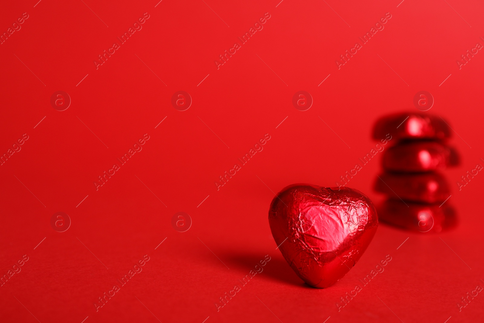 Photo of Tasty chocolate heart shaped candy on red background. Space for text
