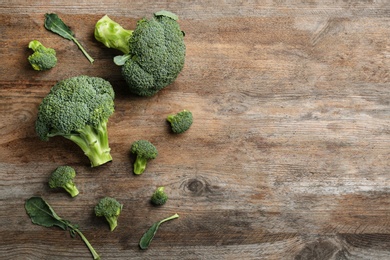 Photo of Fresh raw broccoli florets on wooden table, flat lay with space for text