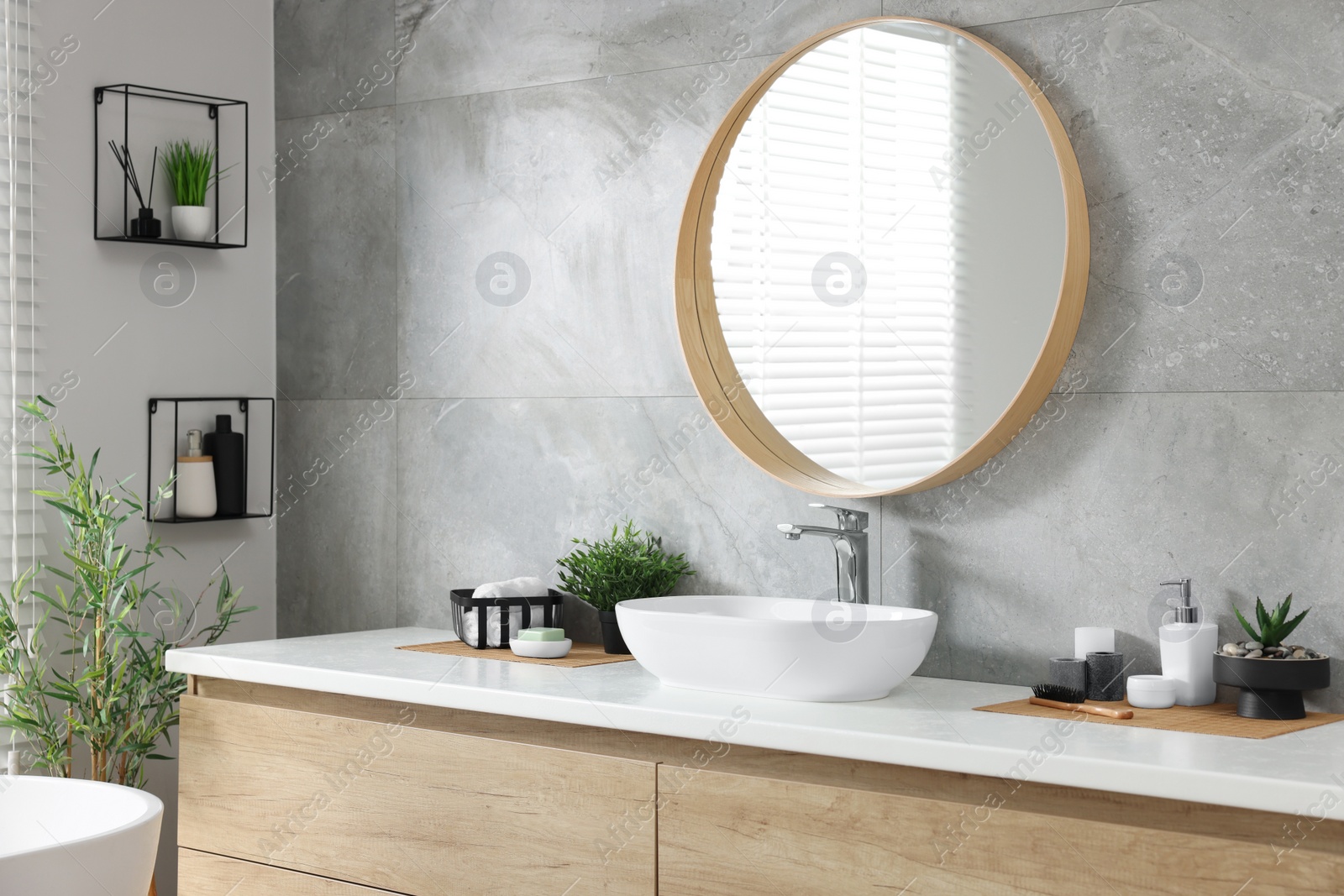 Photo of Potted artificial plants, rolled towels and toiletries near sink on bathroom vanity