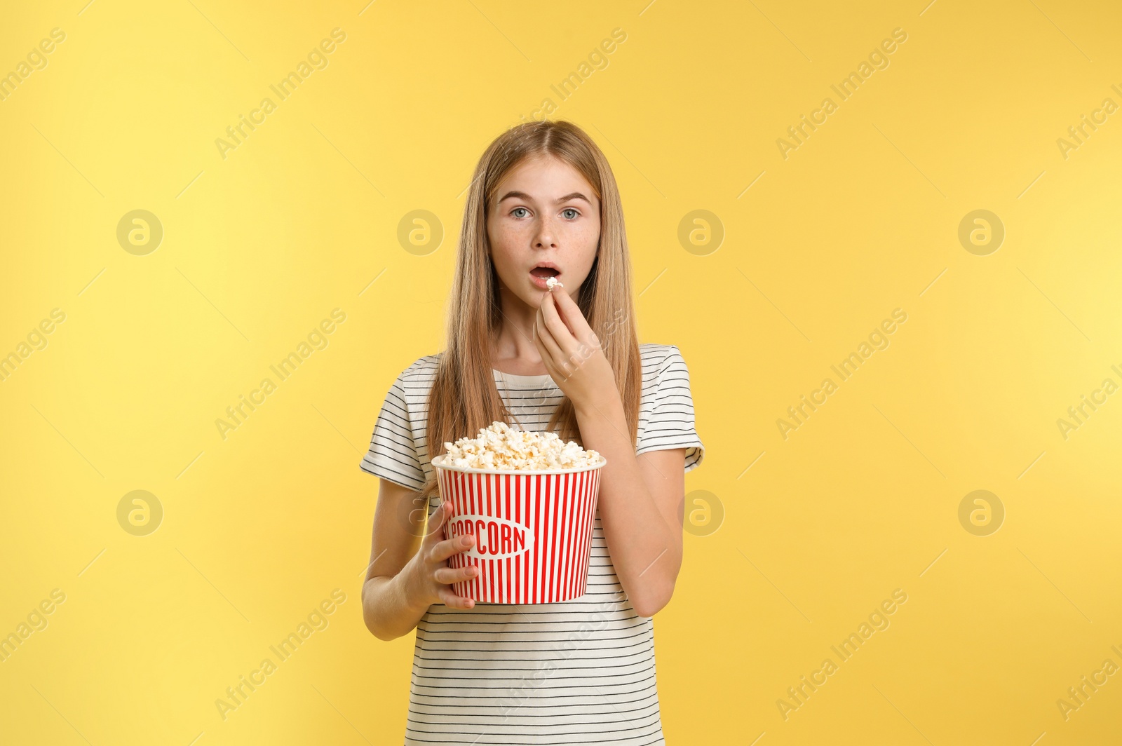 Photo of Emotional teenage girl with popcorn during cinema show on color background