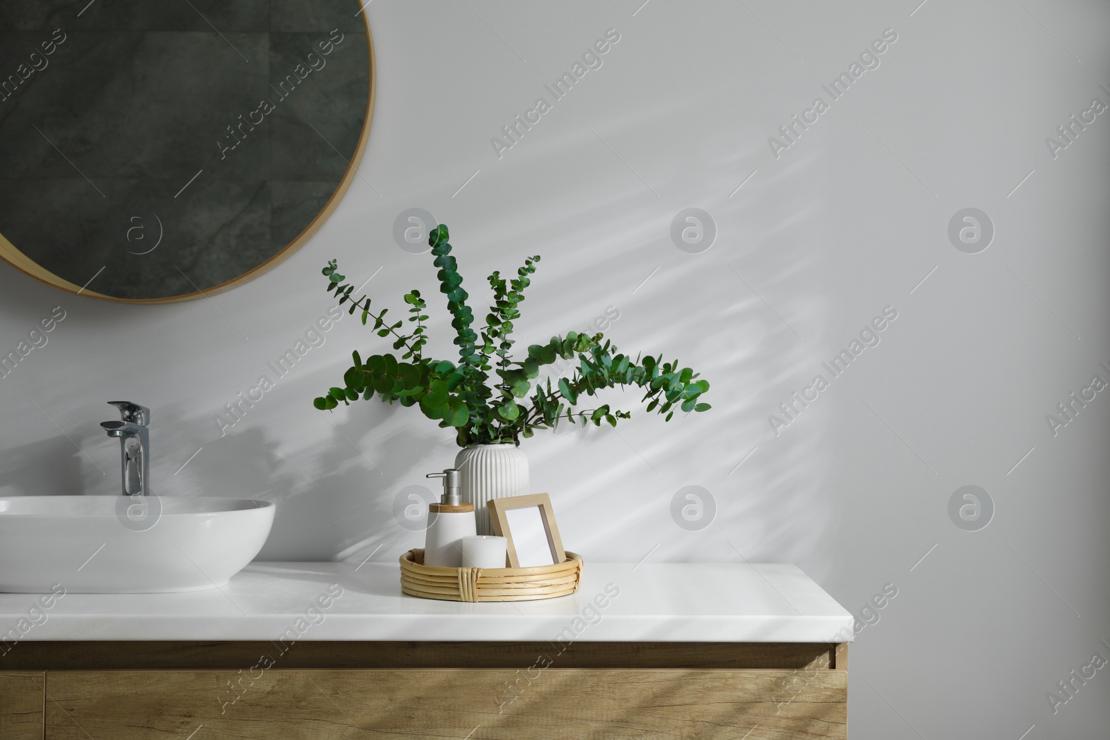 Photo of Stylish mirror, eucalyptus branches and vessel sink in modern bathroom. Interior design