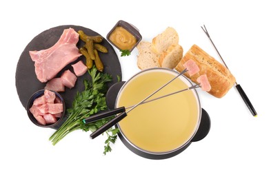 Oil in fondue pot, forks, sauce, pieces of raw meat and other products isolated on white, top view