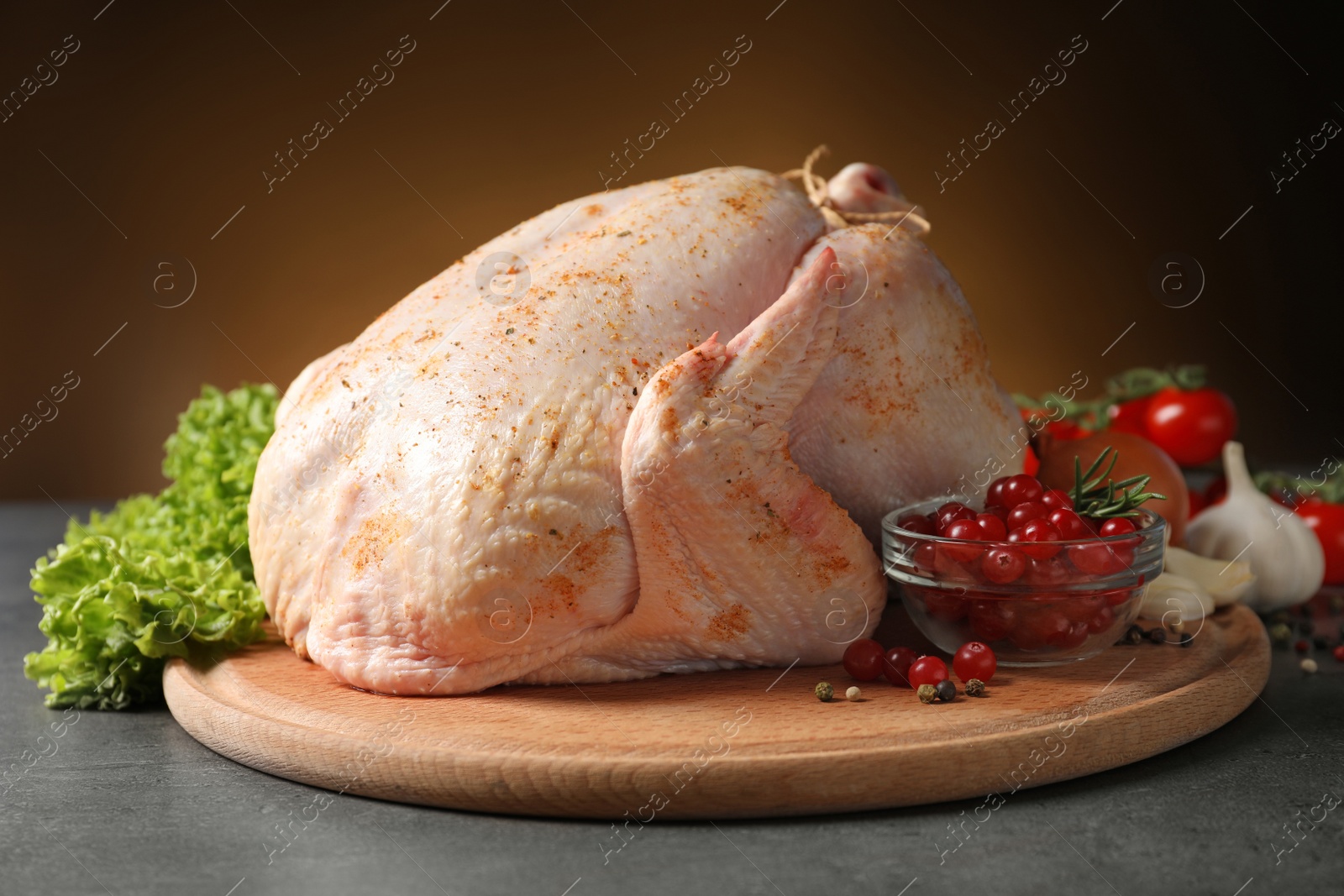 Photo of Wooden board with raw spiced turkey and ingredients on table