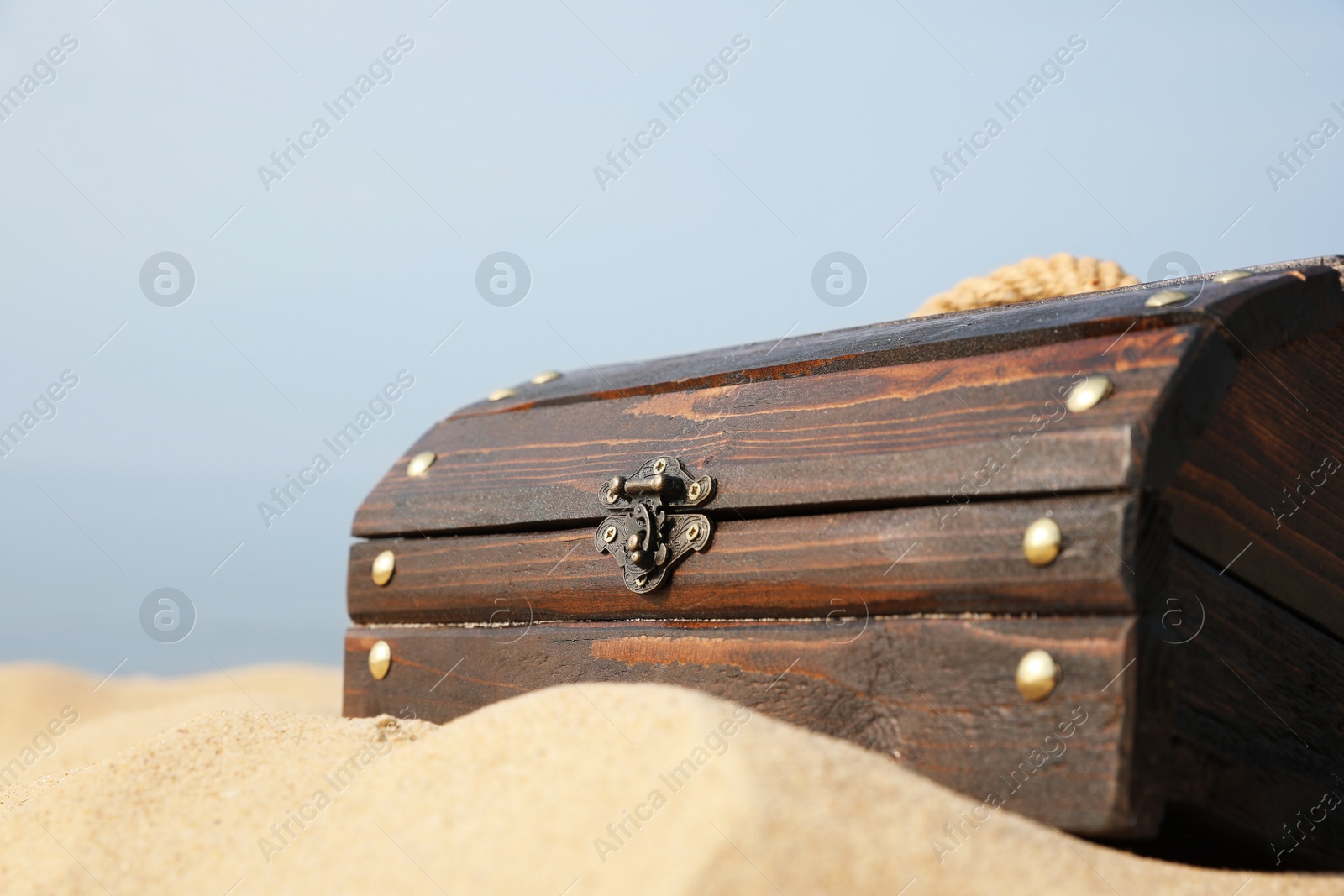 Photo of Closed wooden treasure chest on sandy beach, closeup