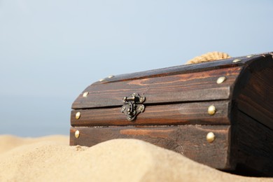 Photo of Closed wooden treasure chest on sandy beach, closeup