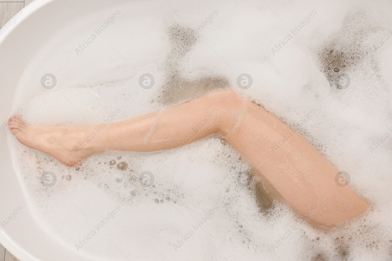 Photo of Woman taking bath with foam in tub, top view