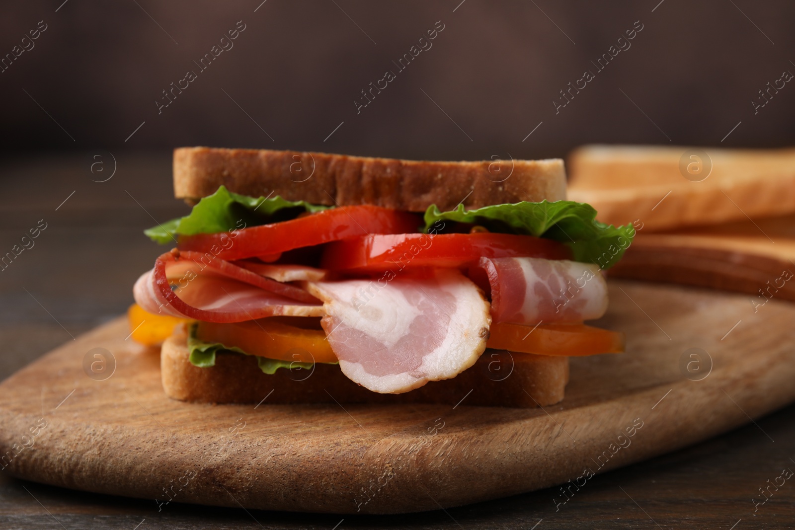 Photo of Tasty sandwich with bacon and tomato on wooden table, closeup