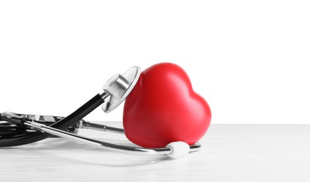 Stethoscope and red heart on wooden table against white background, space for text