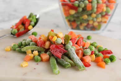 Photo of Mix of different frozen vegetables on white marble table, closeup