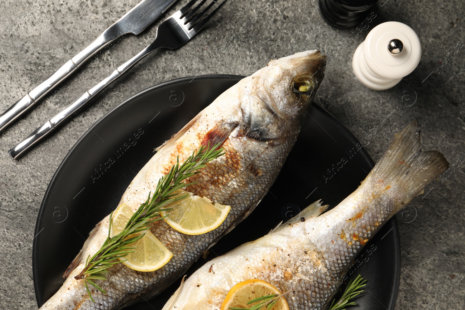 Photo of Delicious baked fish served on grey table, top view