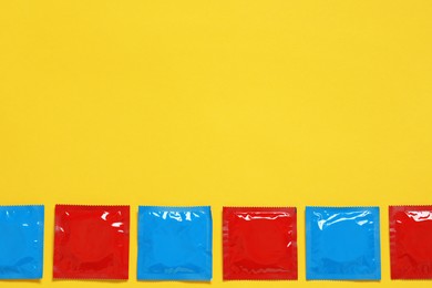 Photo of Condom packages on yellow background, flat lay and space for text. Safe sex