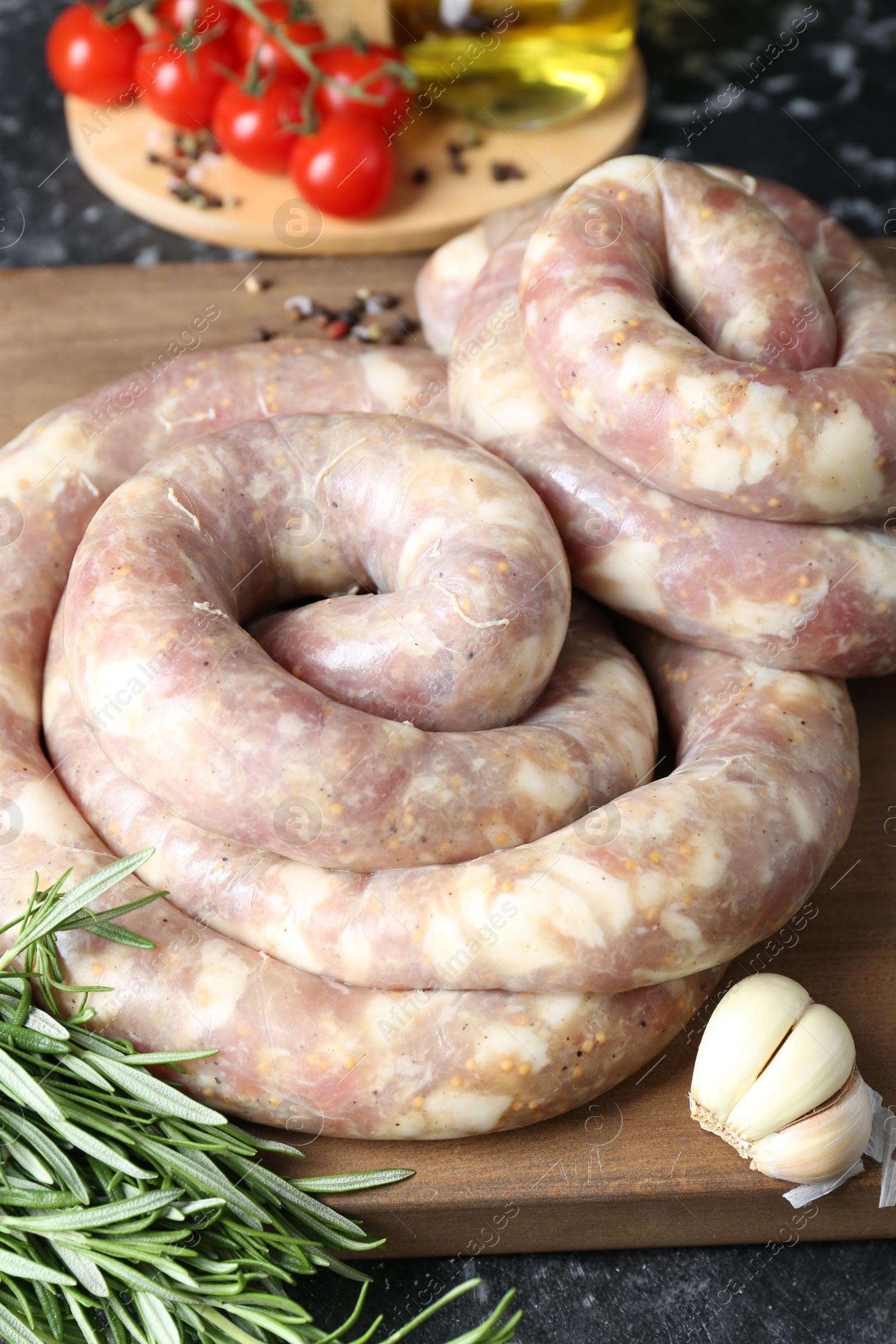 Photo of Raw homemade sausage, spices and other products on grey textured table, closeup