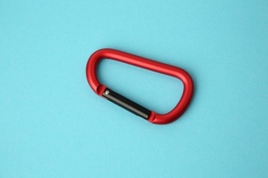 Photo of One red carabiner on light blue background, top view