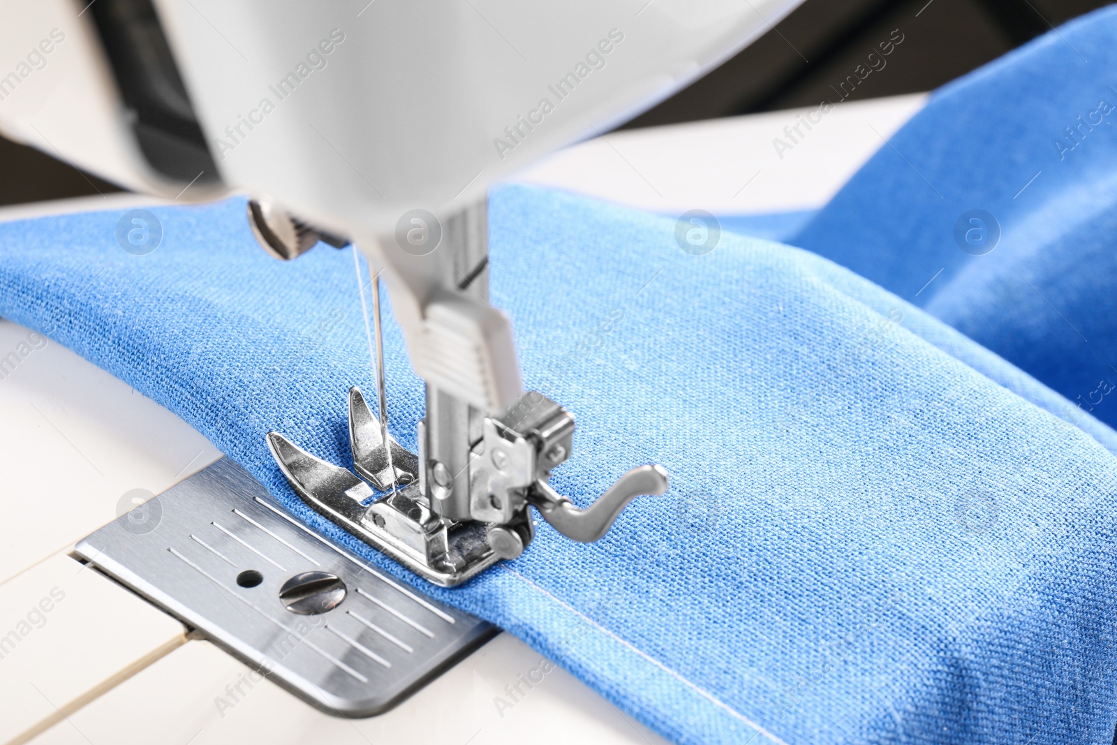 Photo of Sewing machine with light blue cloth, closeup