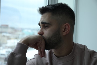 Portrait of sad man near window at home