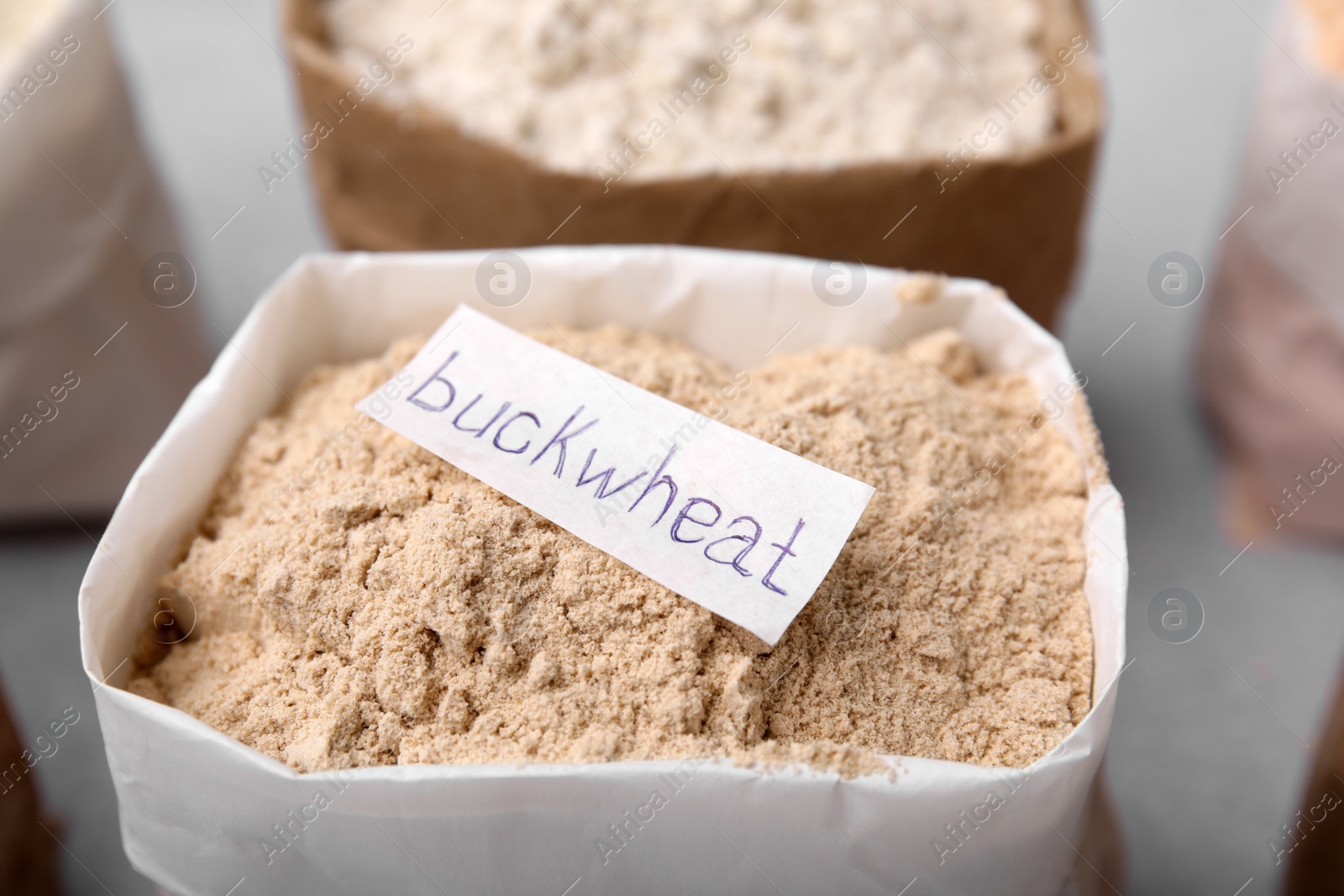 Photo of Sack with buckwheat flour on blurred background, closeup