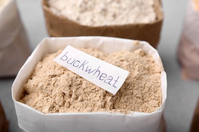 Photo of Sack with buckwheat flour on blurred background, closeup
