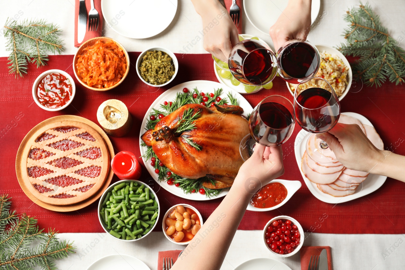 Photo of Women clinking glasses of wine over festive table with delicious roasted turkey, top view