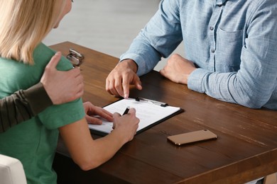 Photo of Notary working with couple at wooden table, closeup