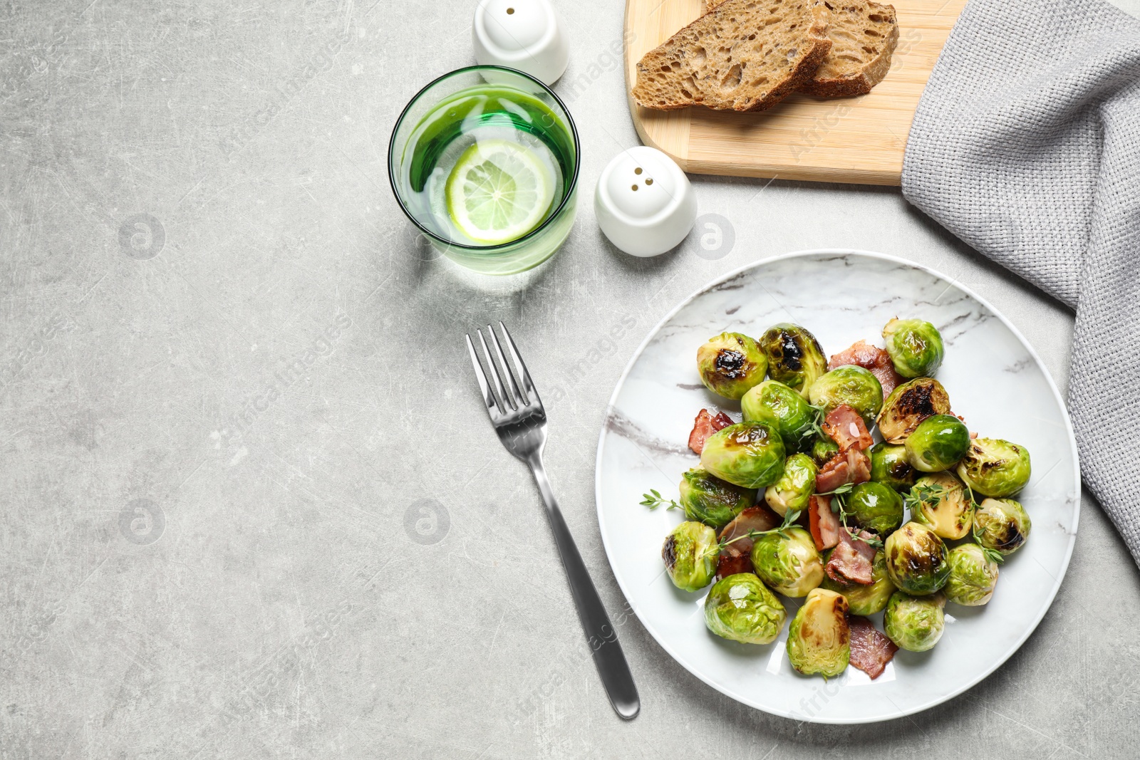 Image of Delicious fried Brussels sprouts with bacon served on grey table, flat lay. Space for text