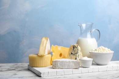 Photo of Fresh dairy products on table against color background