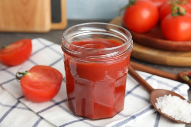 Photo of Composition with tomato sauce in jar on table