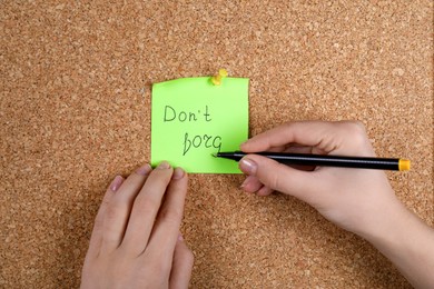 Photo of Woman writing paper note pinned to cork board, closeup