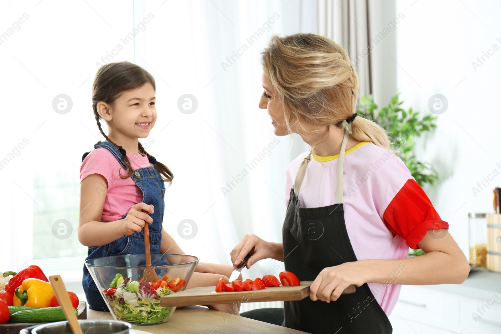 Photo of Young nanny with cute little girl cooking together in kitchen