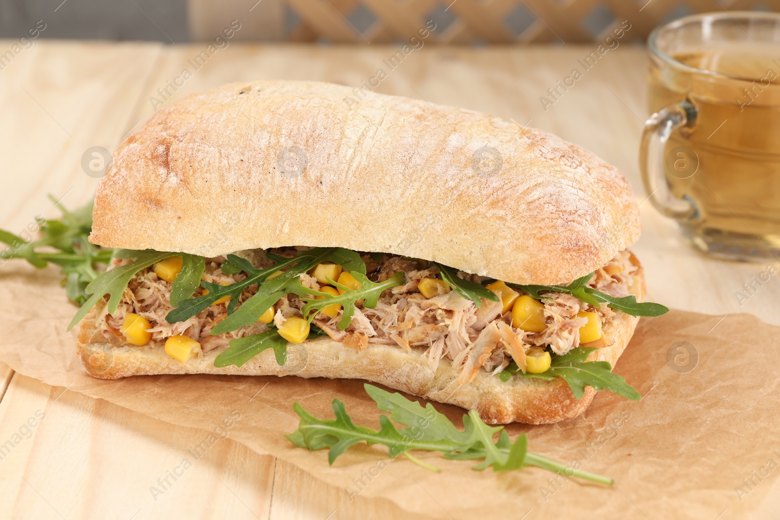 Photo of Delicious sandwich with tuna, corn and greens on white wooden table
