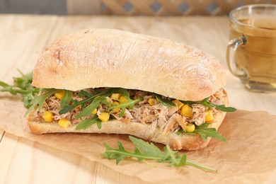 Delicious sandwich with tuna, corn and greens on white wooden table