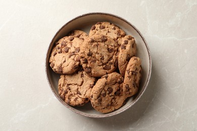 Photo of Delicious chocolate chip cookies in bowl on light grey table, top view