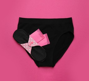 Photo of Women's underwear with disposable and reusable menstrual pads on pink background, top view