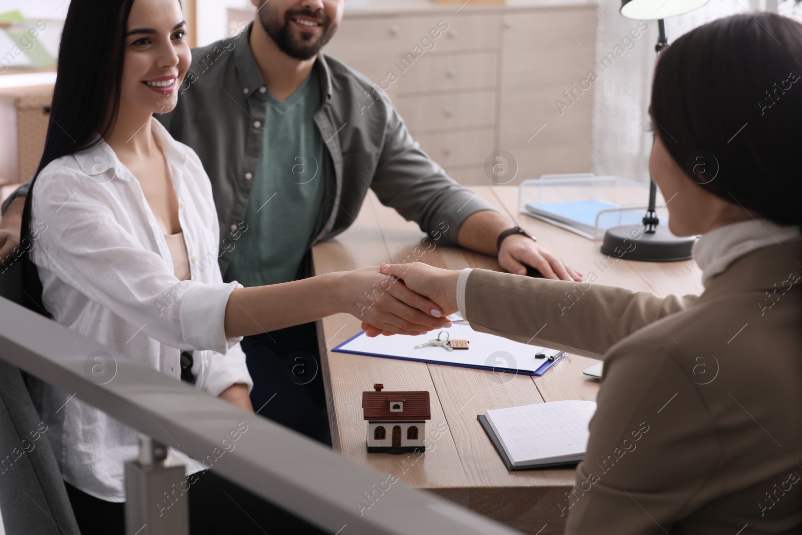 Photo of Real estate agent shaking hands with client in office, closeup. Mortgage concept