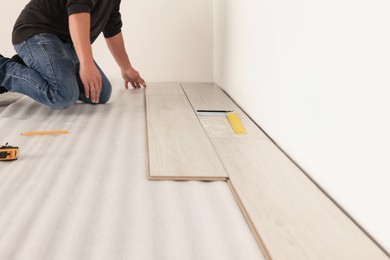 Photo of Professional worker installing new laminate flooring, closeup