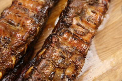 Photo of Tasty grilled pork ribs on wooden board, closeup