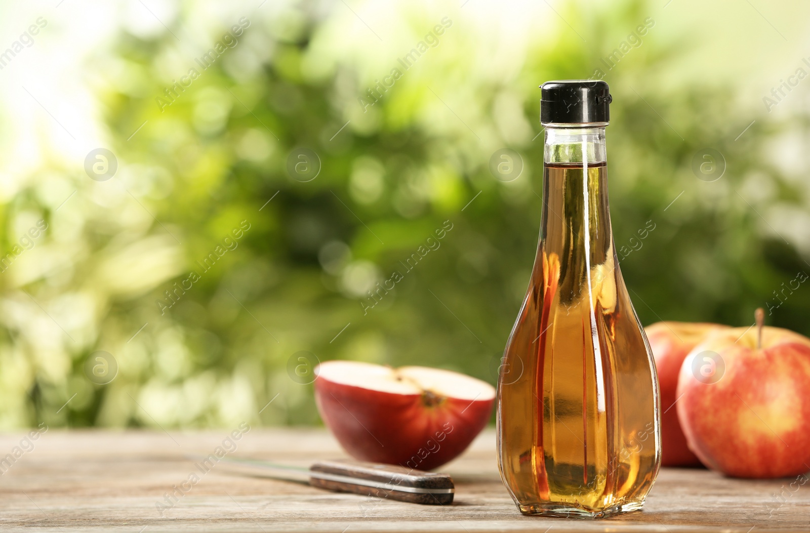 Photo of Composition with bottle of apple vinegar on table. Space for text