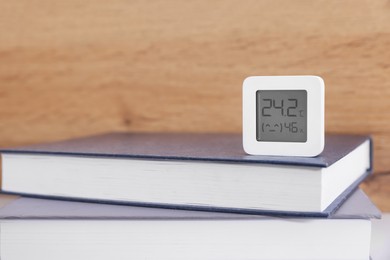 Photo of Digital hygrometer with thermometer on books. Space for text