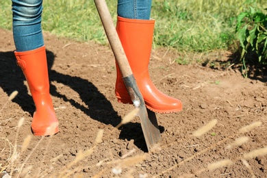 Photo of Woman digging soil with shovel outdoors. Gardening tool