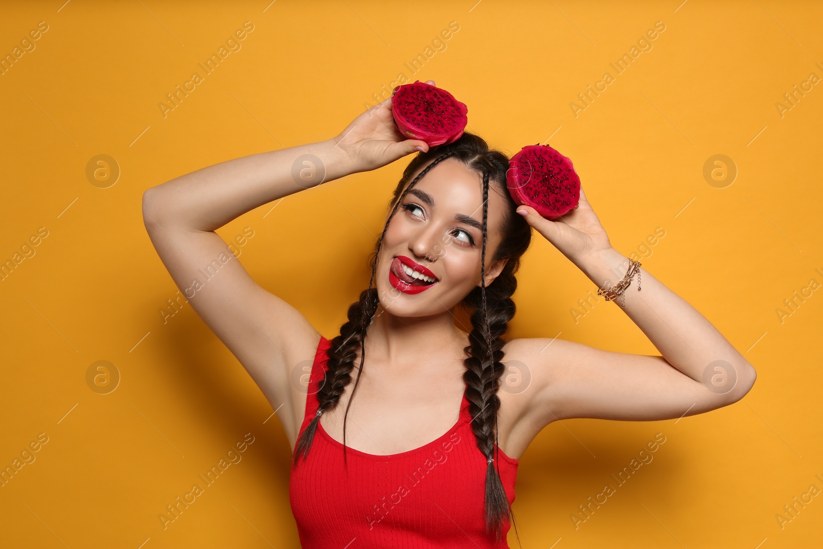 Photo of Young woman with fresh pitahaya on yellow background. Exotic fruit