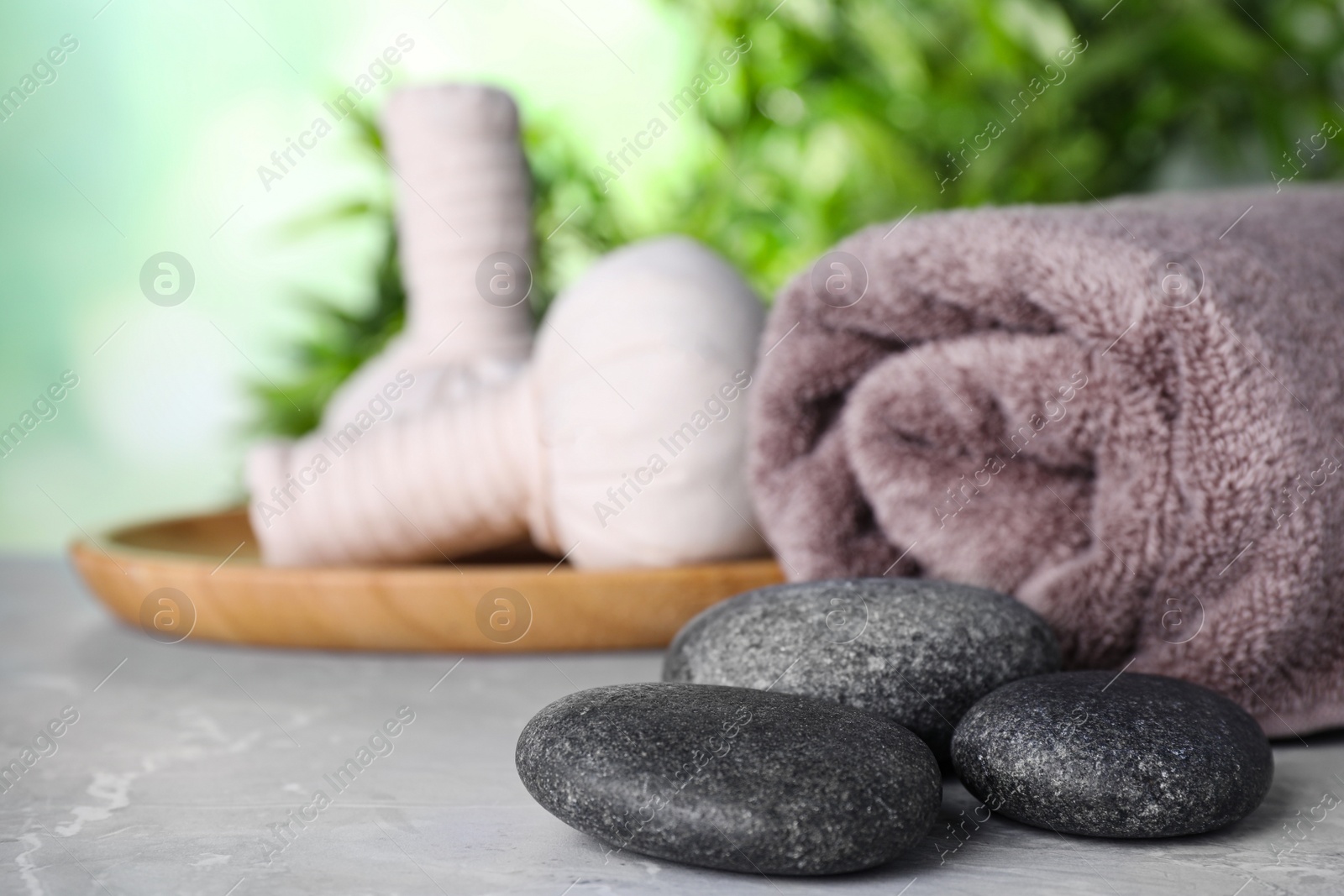 Photo of Spa stones, towel and herbal bags on grey marble table, space for text