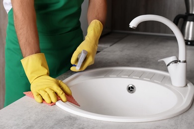 Photo of Man cleaning kitchen sink with rag, closeup