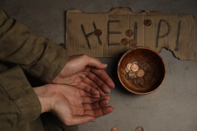 Photo of Poor homeless woman begging for money. Cardboard help sign and bowl with donations near her, top view