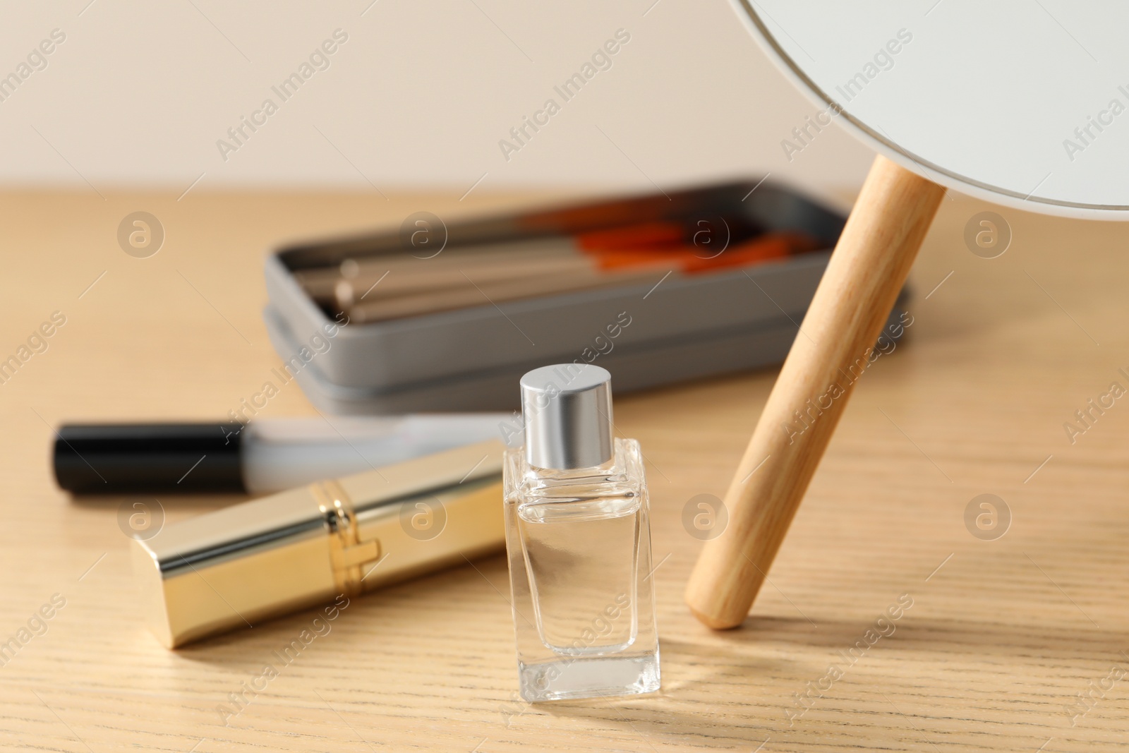 Photo of Makeup products and perfume on wooden dressing table, closeup