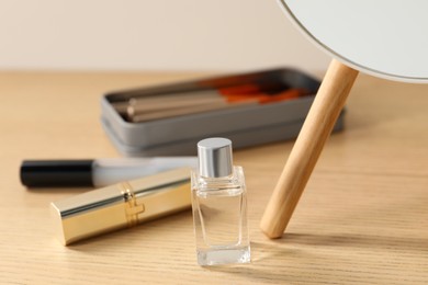 Makeup products and perfume on wooden dressing table, closeup