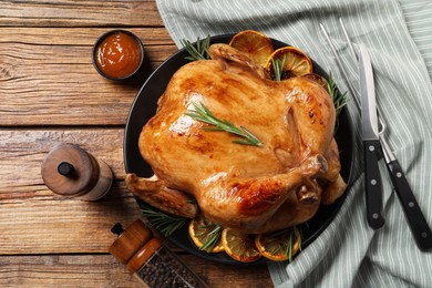Photo of Tasty roasted chicken with rosemary and lemon served on wooden table, flat lay