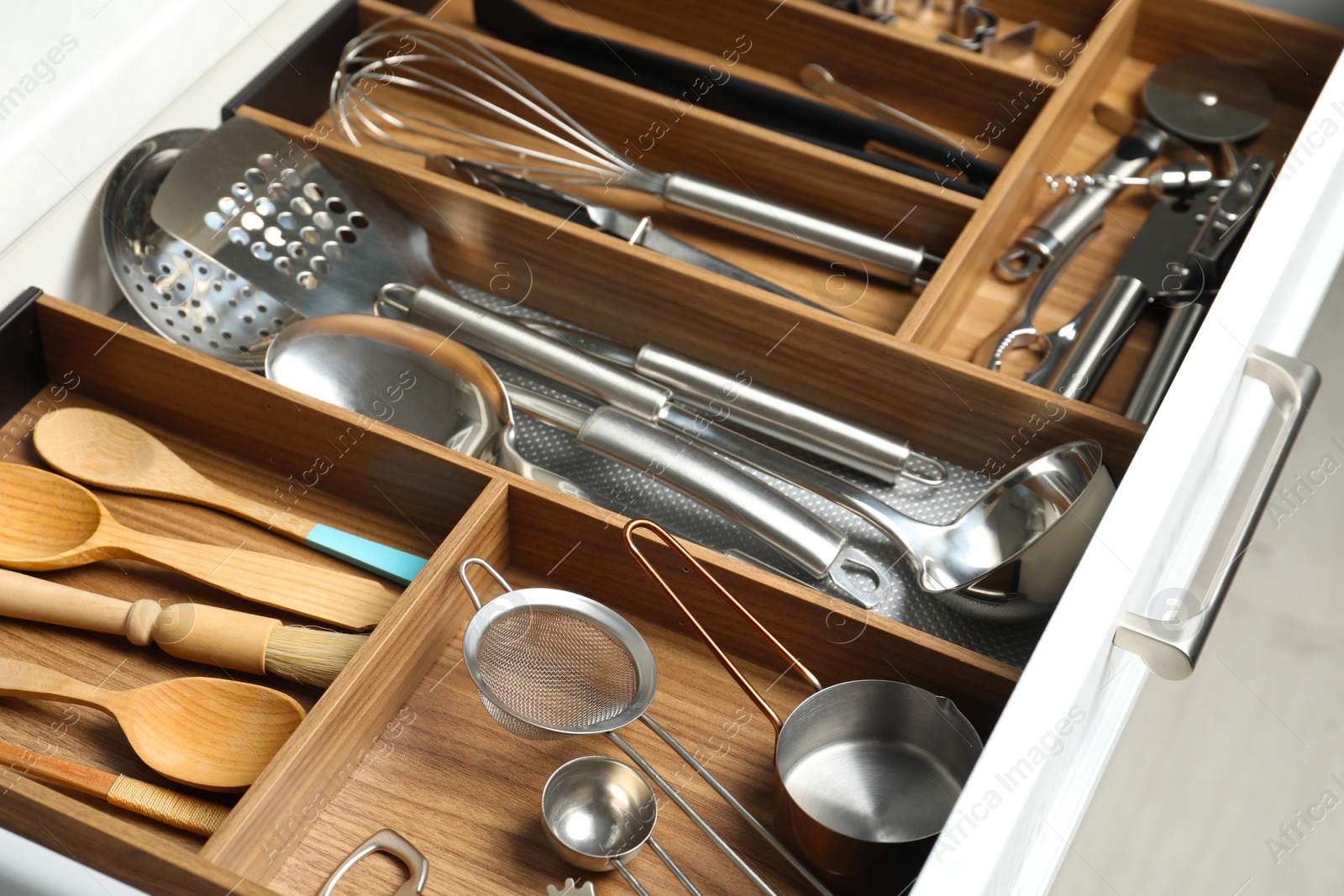 Photo of Different utensils in open desk drawer indoors, closeup