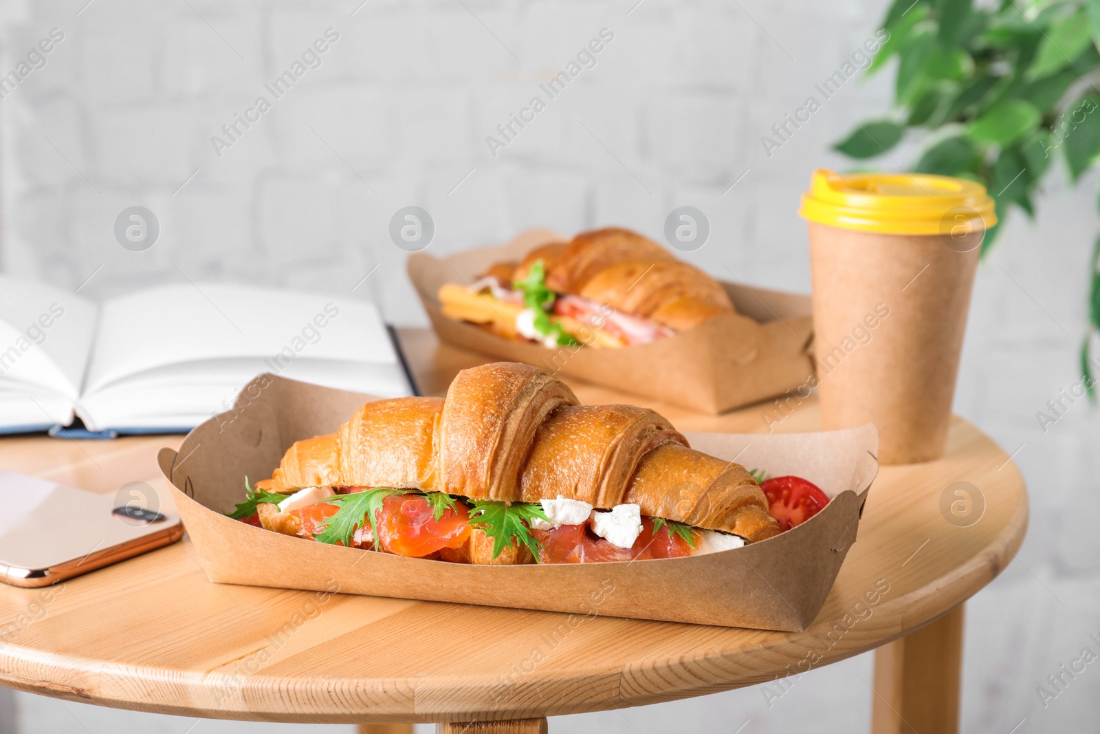 Photo of Tasty croissant sandwich with red fish on wooden table