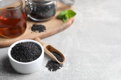 Photo of Black sesame seeds and oil on grey table, space for text