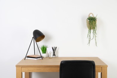 Photo of Comfortable workplace with wooden desk near white wall at home