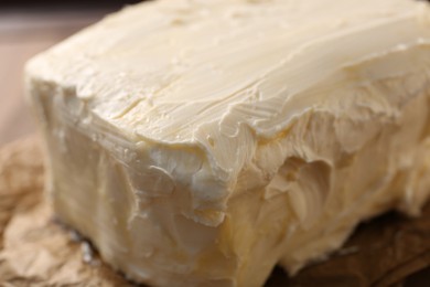 Photo of Piece of tasty homemade butter on parchment, closeup view